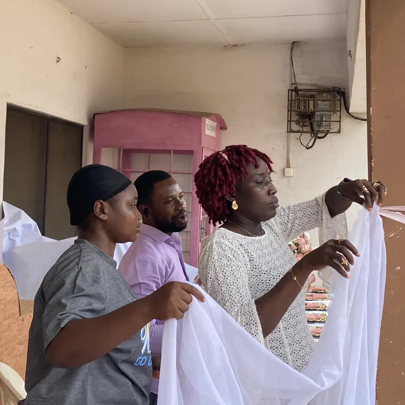 Trainees practising fabric draping with a length of white voile