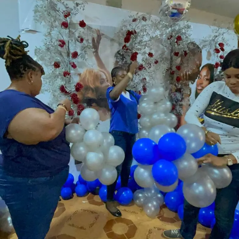 Trainees building a blue and white balloon garland against a decorated wall