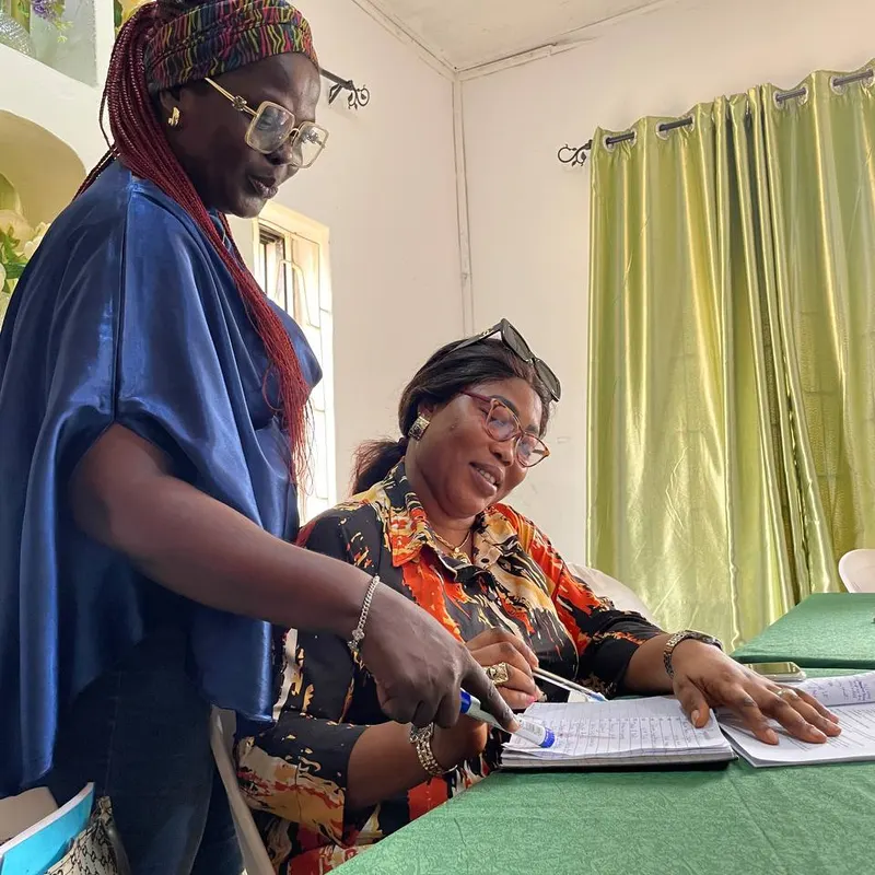 Trainer leaning over a desk to guide a trainee through her workbook