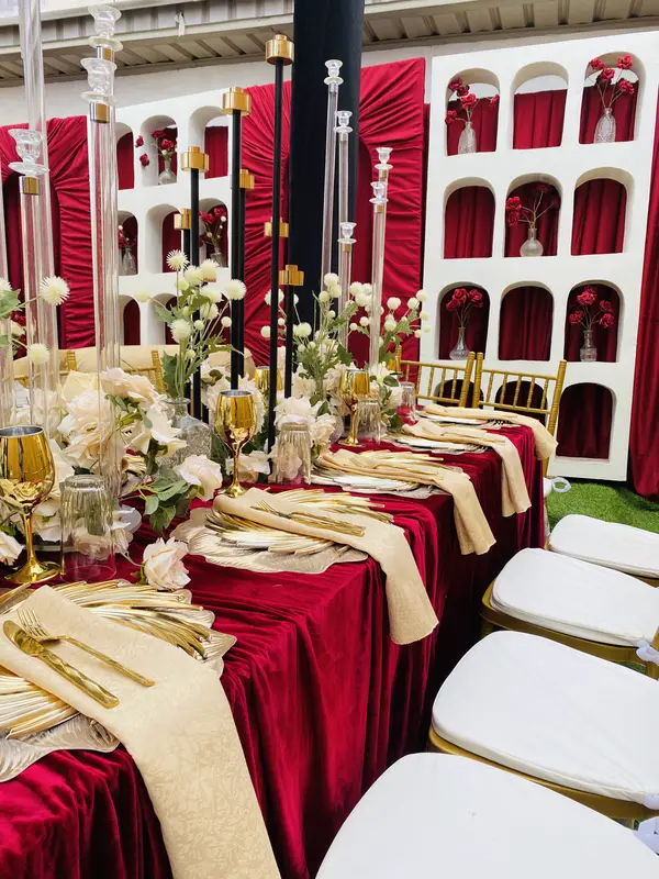 Close-up of birthday place setting with gold sunburst chargers, crystal candelabras and white roses on red velvet