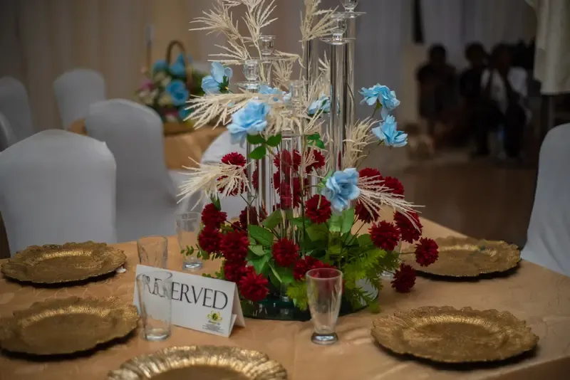 Reserved table centerpiece with red and blue florals over gold charger plates