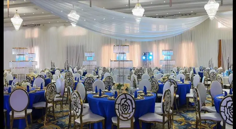 Sweeping white ceiling drapes and crystal chandeliers over royal blue banquet seating