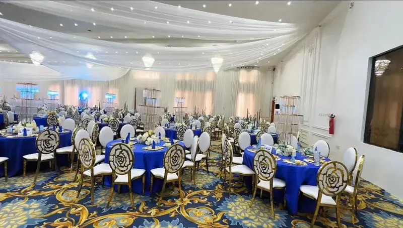 Spacious reception hall styled with white drapery, gold chairs and royal blue linens