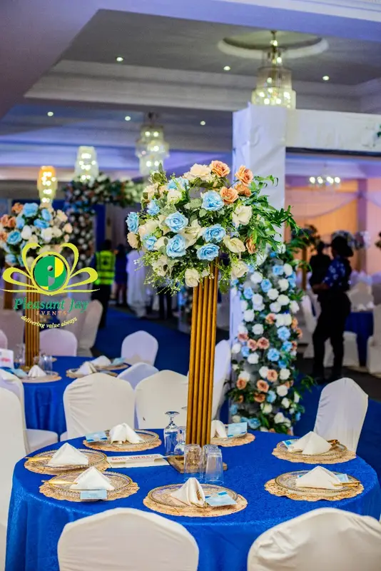 Royal blue tablescape with gold charger plates and towering rose centerpiece