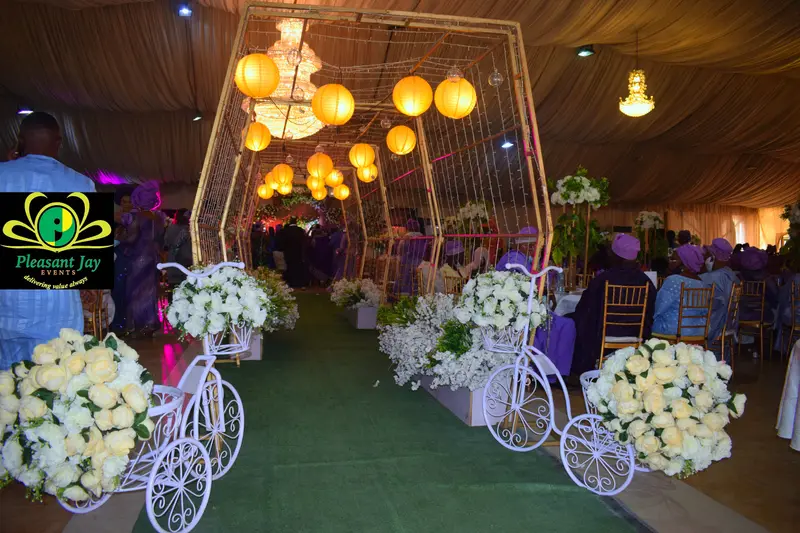 Reception aisle with white floral bicycle stands and cream roses under a lantern canopy