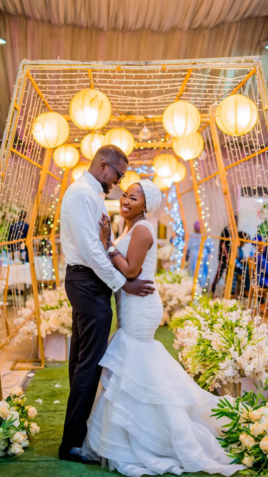 Bride and groom under a golden lantern canopy