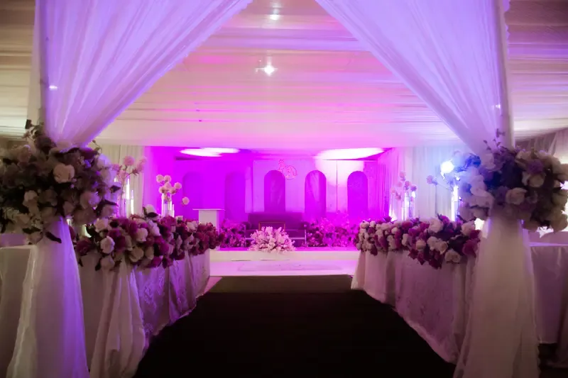 Purple-lit wedding stage with a flower-lined walkway